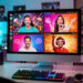 Écran d’ordinateur affichant plusieurs fenêtres colorées de diffusion gaming dans un studio lumineux, avec des animateurs et une représentation abstraite du public en ligne.